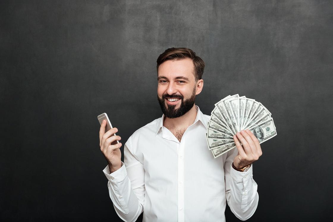 Мужчина держит смартфон и деньги
