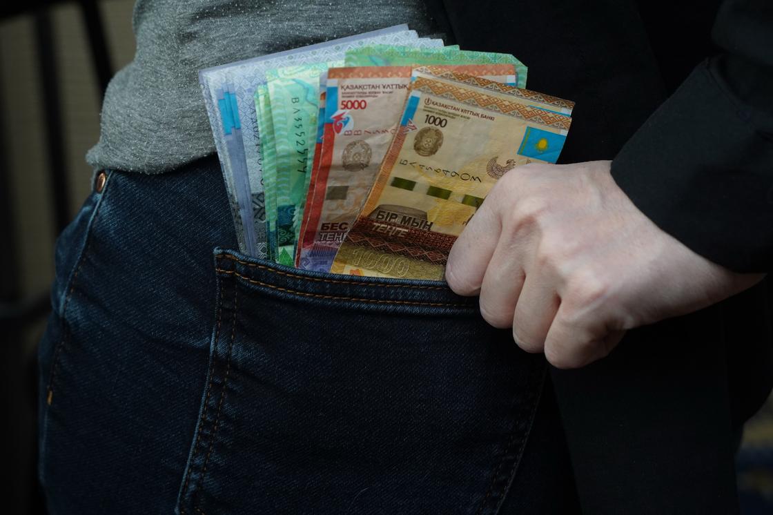 Мужчина кладет деньги в задний карман