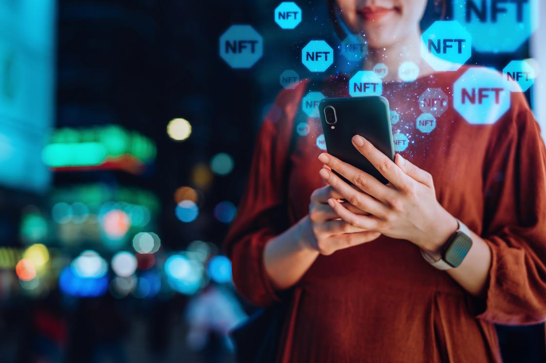 Девушка покупает NFT с помощью мобильного телефона Девушка покупает NFT с помощью мобильного телефона