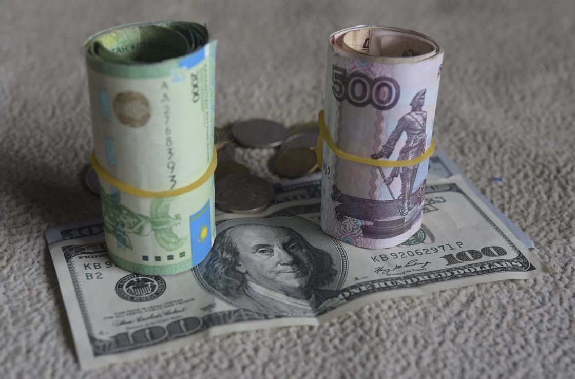 Завернутые купюры тенге и рублей стоят на долларе Завернутые купюры тенге и рублей стоят на долларе