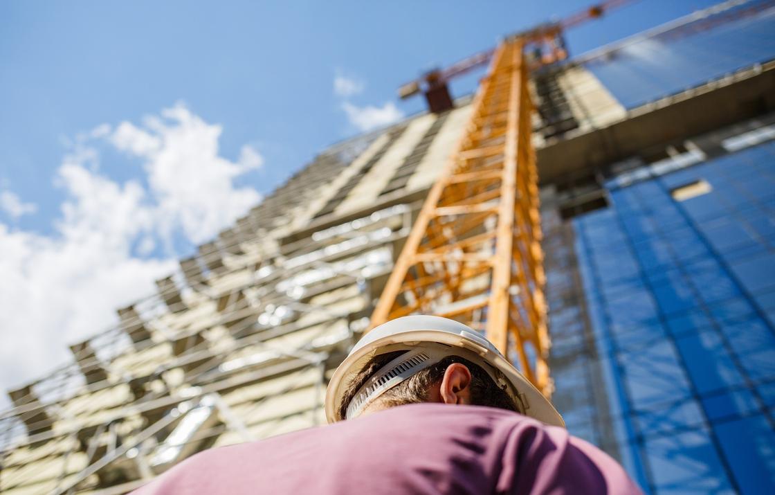 Строитель на фоне стройки высотного здания Строитель на фоне стройки высотного здания