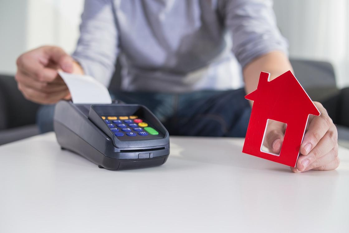 Мужчина держит чек и картонный дом Мужчина держит чек и картонный дом