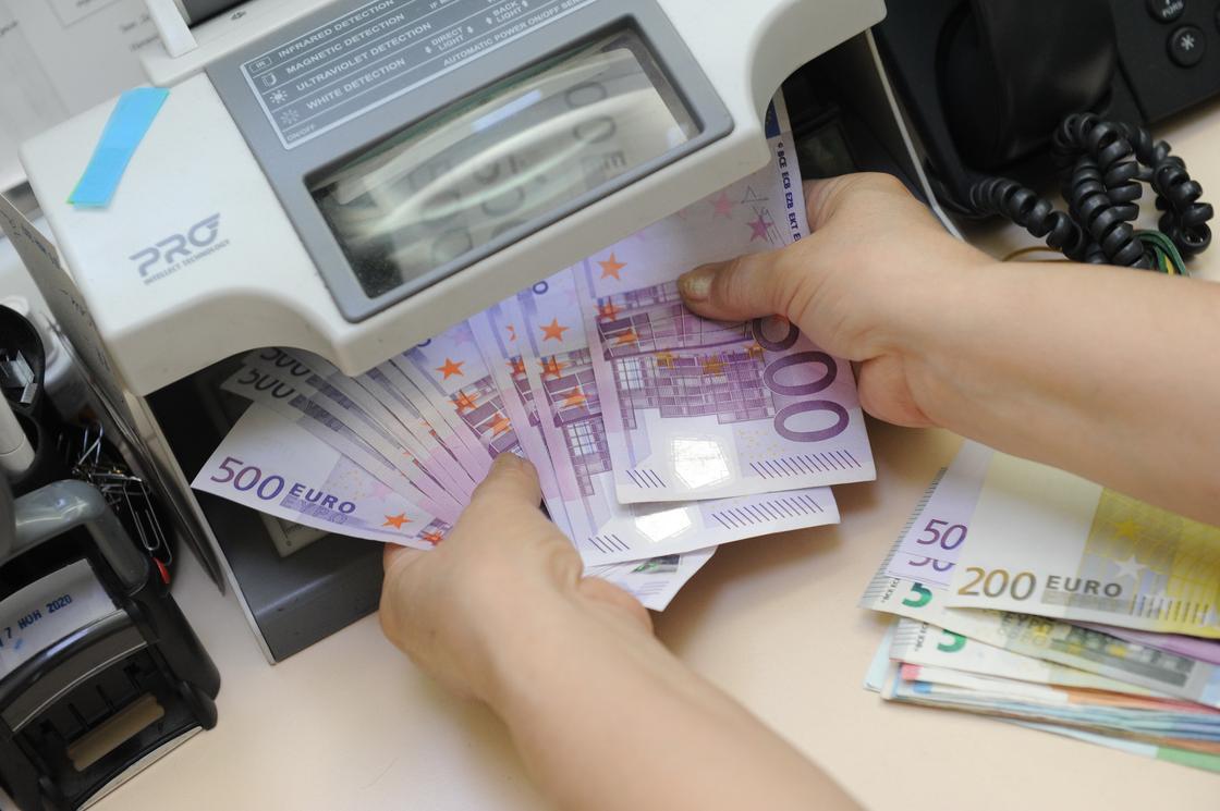 Кассир проверяет евро