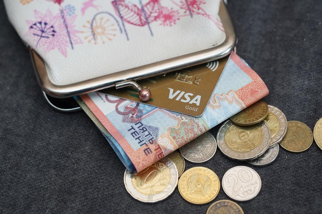 Банковская карта и купюра тенге лежат в кошельке