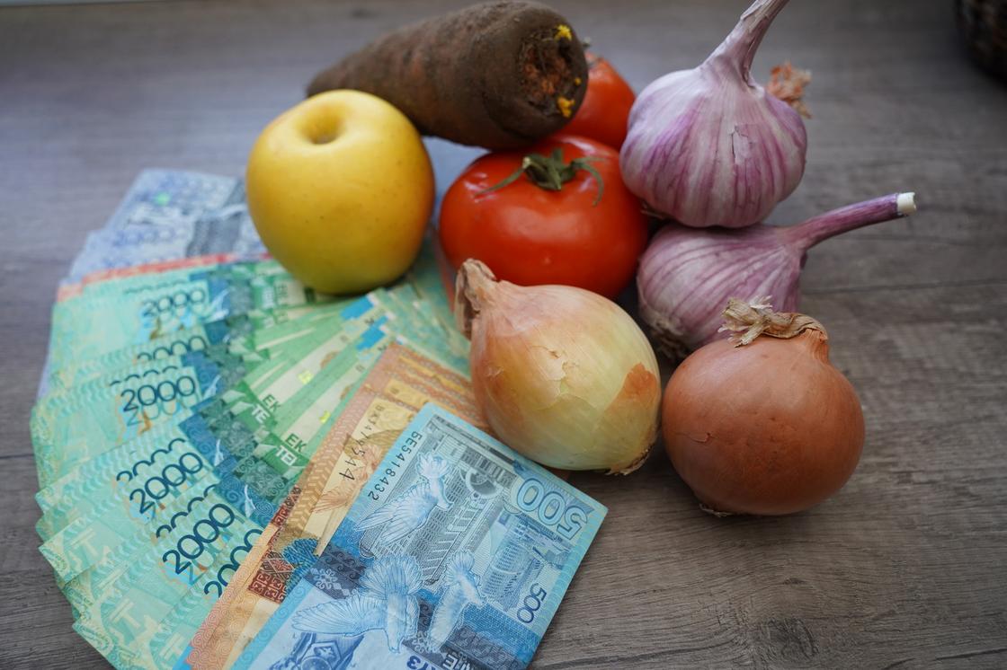 Овощи лежат рядом с купюрами тенге Овощи лежат рядом с купюрами тенге