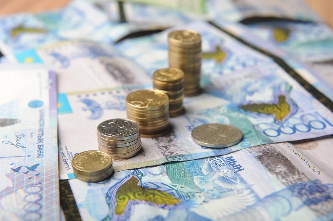 стопки монет стоят на купюрах тенге